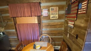 Interior de una cabaña de madera con una mesa de comedor, sillas y techo de madera.