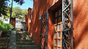 A staircase leading to a building with red stucco walls and metal gates. - Beautiful River-front Apartment with Natural Pool (Sorède)