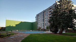 A building with a green facade, a swimming pool, and a grassy area. - Apartment towers, wifi, pool, breakfast. (Calahorra)