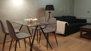 A modern living room with a glass dining table, grey chairs, a black floor lamp, and a black sofa. - Apartment towers, wifi, pool, breakfast. (Calahorra)
