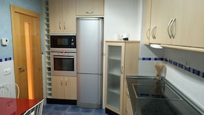 A compact kitchen with a refrigerator, oven, microwave, and a small dining table with chairs. - Apartment towers, wifi, pool, breakfast. (Calahorra)
