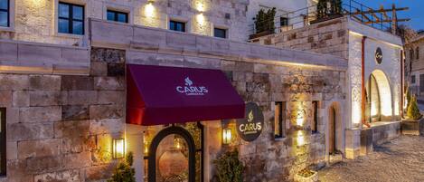 A stone building with a red awning labeled "CARUS CAPPADOCIA" and a sign above the entrance.