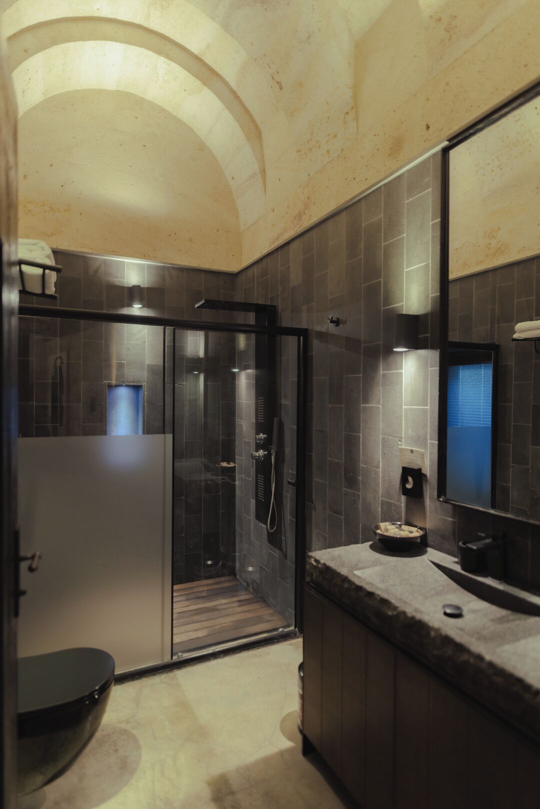 A modern bathroom with a glass shower enclosure, a vanity with a mirror, and a recessed ceiling.
