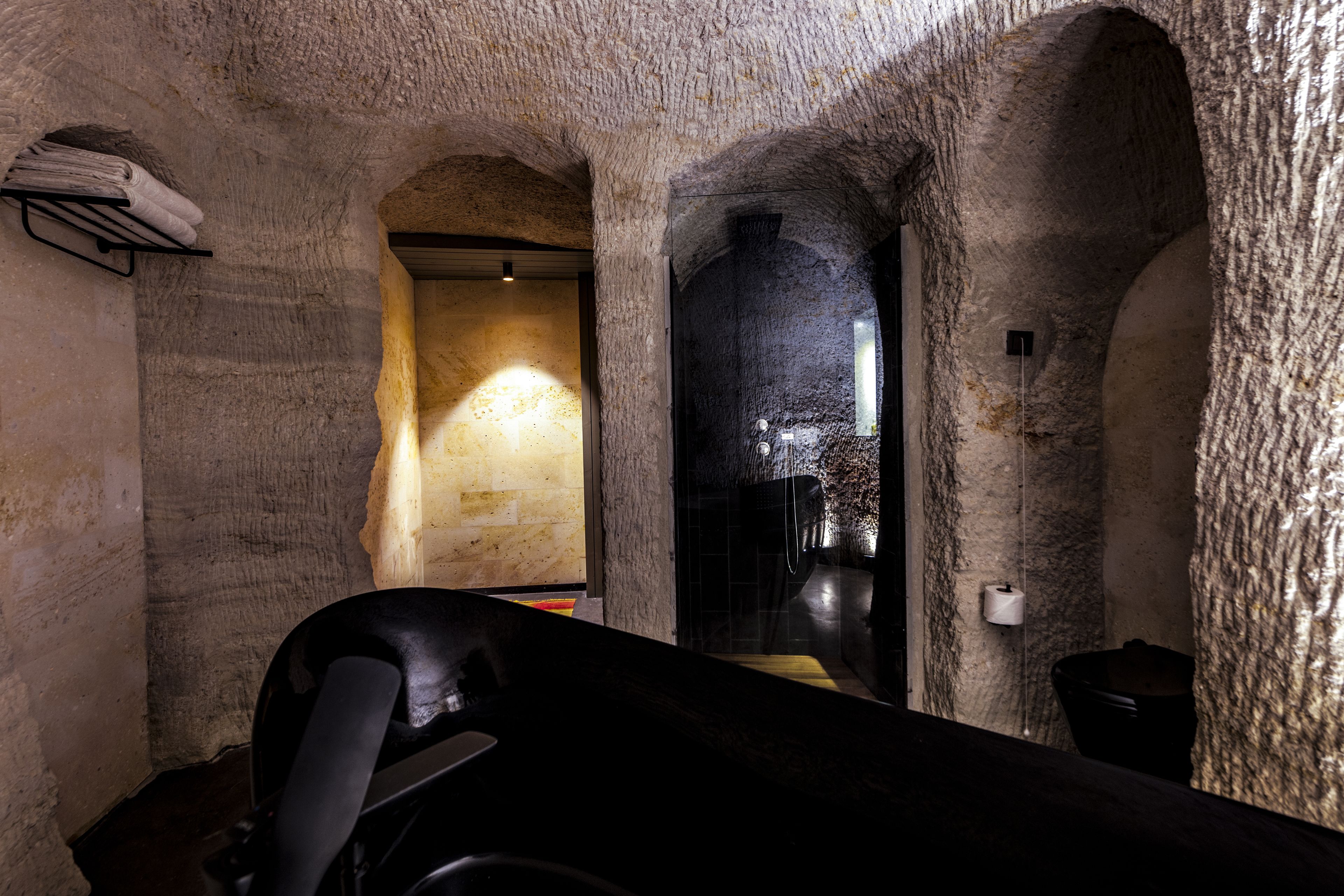 Interior de paredes de piedra con un banco, un perchero y un inodoro.