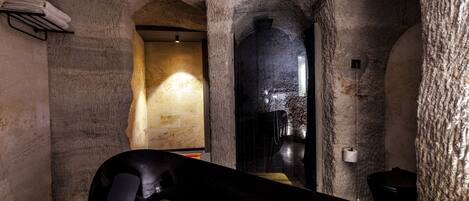 Interior de paredes de piedra con un banco, un perchero y un inodoro.