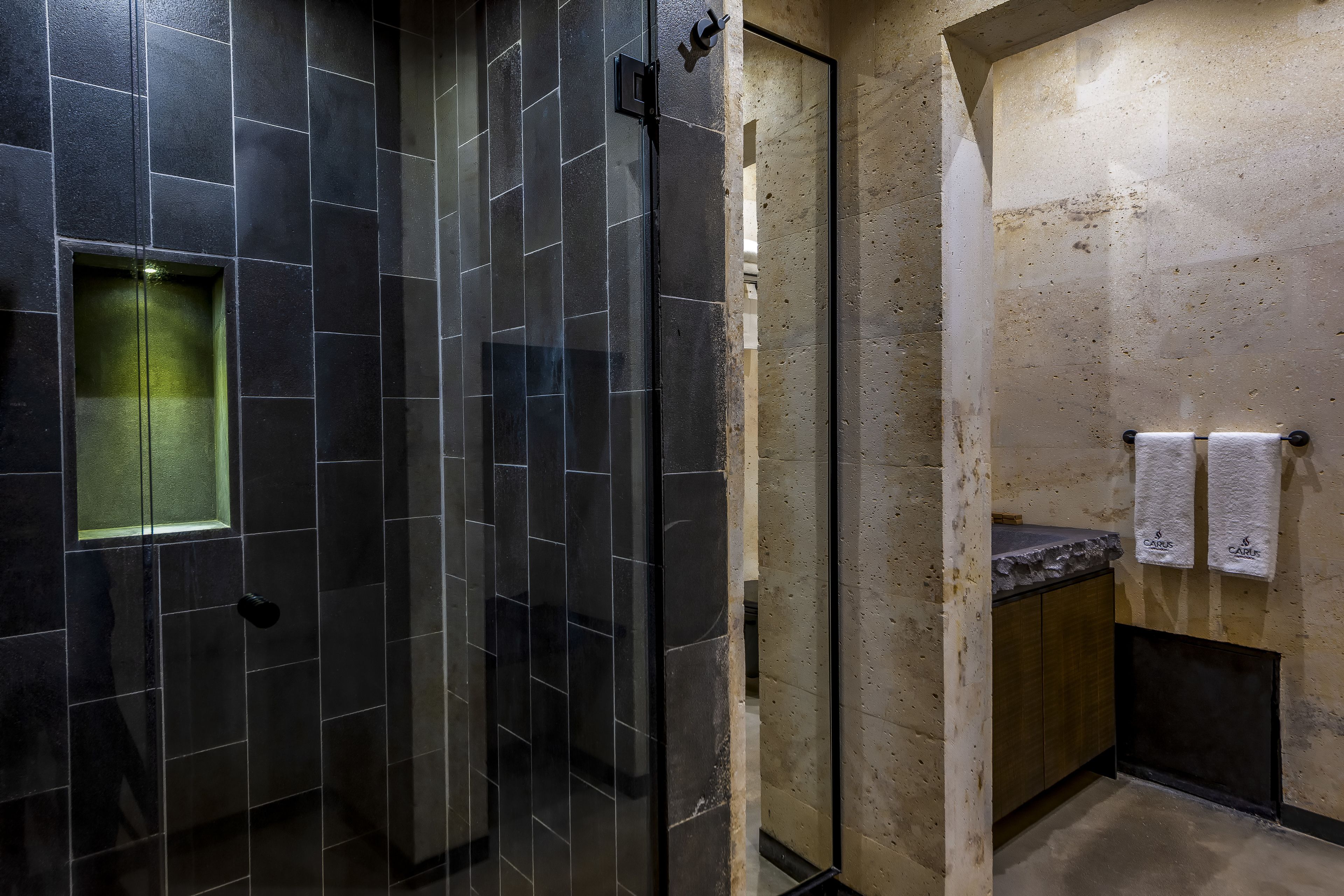 A modern bathroom with a glass-enclosed shower, a wooden vanity, and a towel rack.