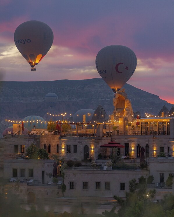 A building with multiple balconies, outdoor seating, and string lights. - Carus Cappadocia (Nevsehir)
