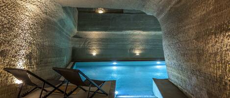 An indoor swimming pool with a unique arched ceiling and a small viewing window.