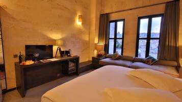 Una habitación de hotel con una cama grande, un escritorio con televisor y una zona de estar junto a la ventana.