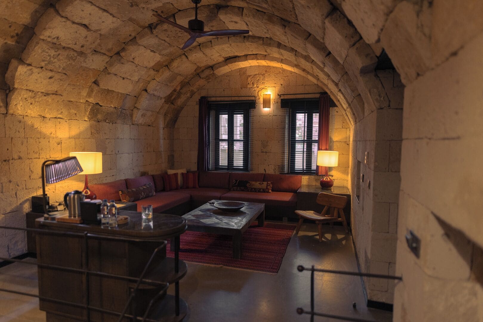 A cozy room with a stone arch ceiling, a sofa set, a coffee table, and two lamps.