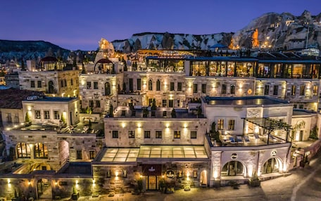 A multi-story hotel with a central courtyard, stone facades, and a mountain backdrop.
