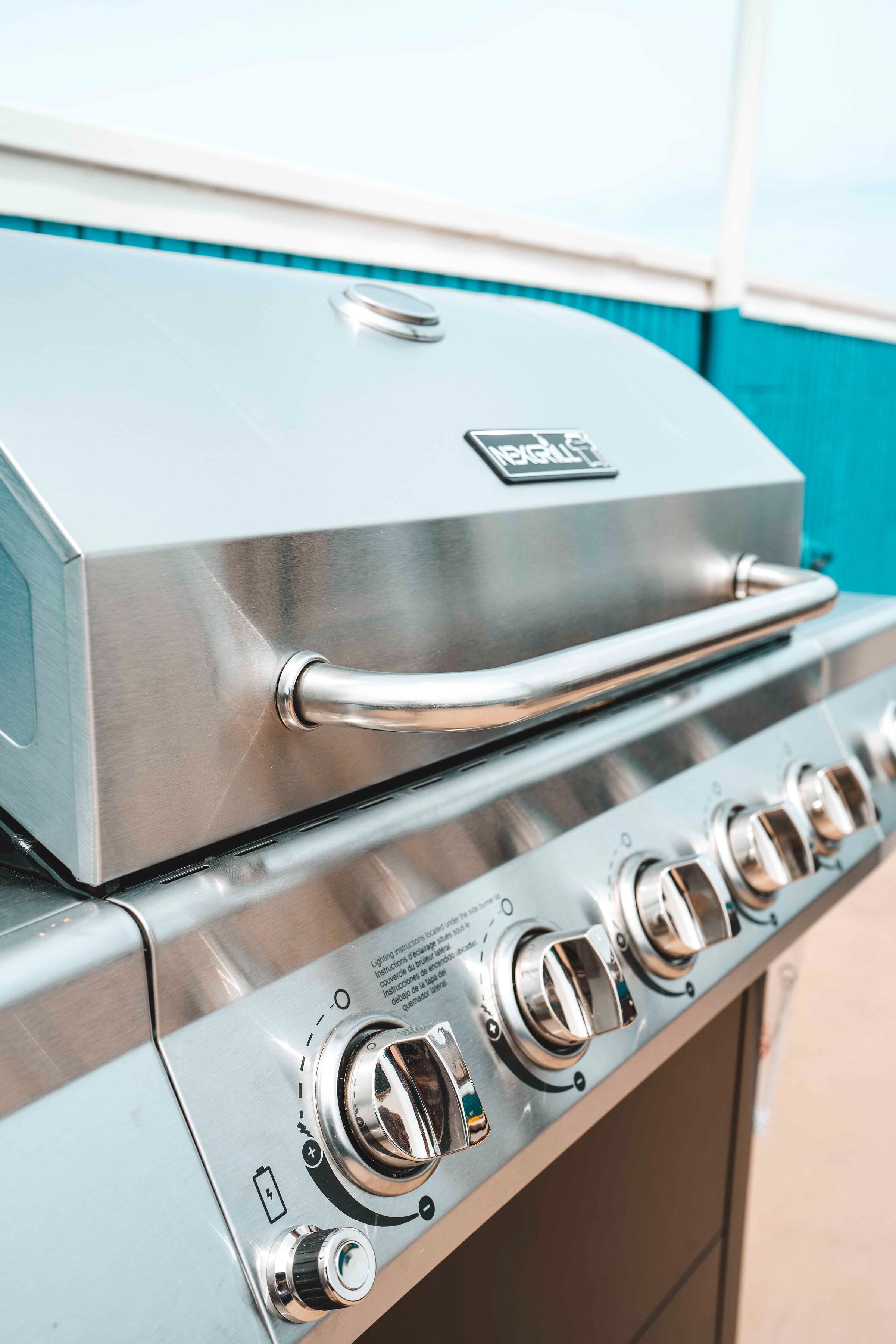 A stainless steel grill with a handle and control knobs.