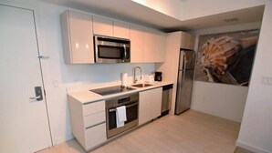 A modern kitchen with white cabinetry, stainless steel appliances, and a tiled floor. - 2 Bedroom Unit Across From Ocean @ Beachwalk Resort (Hallandale Beach)