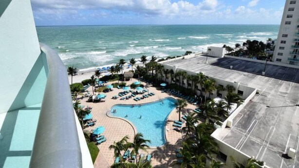 A pool area with lounge chairs and palm trees, overlooking the ocean. - Spectacular 1 Bed 1 Bath @ Tides (Hollywood)