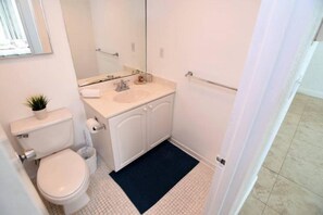 A small, clean bathroom with a toilet, sink, and mirror. - Spectacular 1 Bed 1 Bath @ Tides (Hollywood)