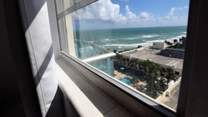 A view of the ocean from a window, with a pool and buildings in the background. - Spectacular 1 Bed 1 Bath @ Tides (Hollywood)