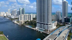 Un hôtel de grande hauteur au design moderne, situé près d’un front de mer avec un port de plaisance.