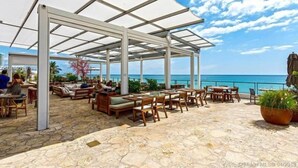 An outdoor patio with stone flooring, wooden furniture, and a white canopy. - Hyde -3308  2 Beds/ 2 Baths Unit At The Hyde Beach Resort And Residences (Hollywood)