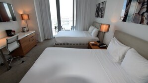 Une chambre d’hôtel avec deux lits, un bureau avec une chaise, une lampe et un téléviseur.