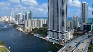 A high-rise hotel with a modern design, located near a waterfront with a view of the ocean and other buildings.