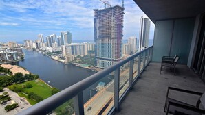 A balcony with a view of a cityscape, including a river and high-rise buildings.