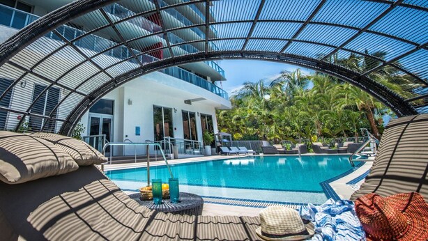 A pool area with lounge chairs and a covered seating area.