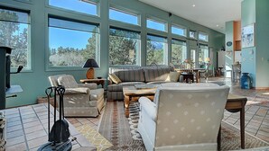 Un salón comedor amplio con ventanas grandes, una chimenea y diversas opciones de asientos.