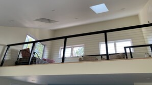 Una habitación amplia con techo alto, ventanas grandes y un balcón con barandilla negra.