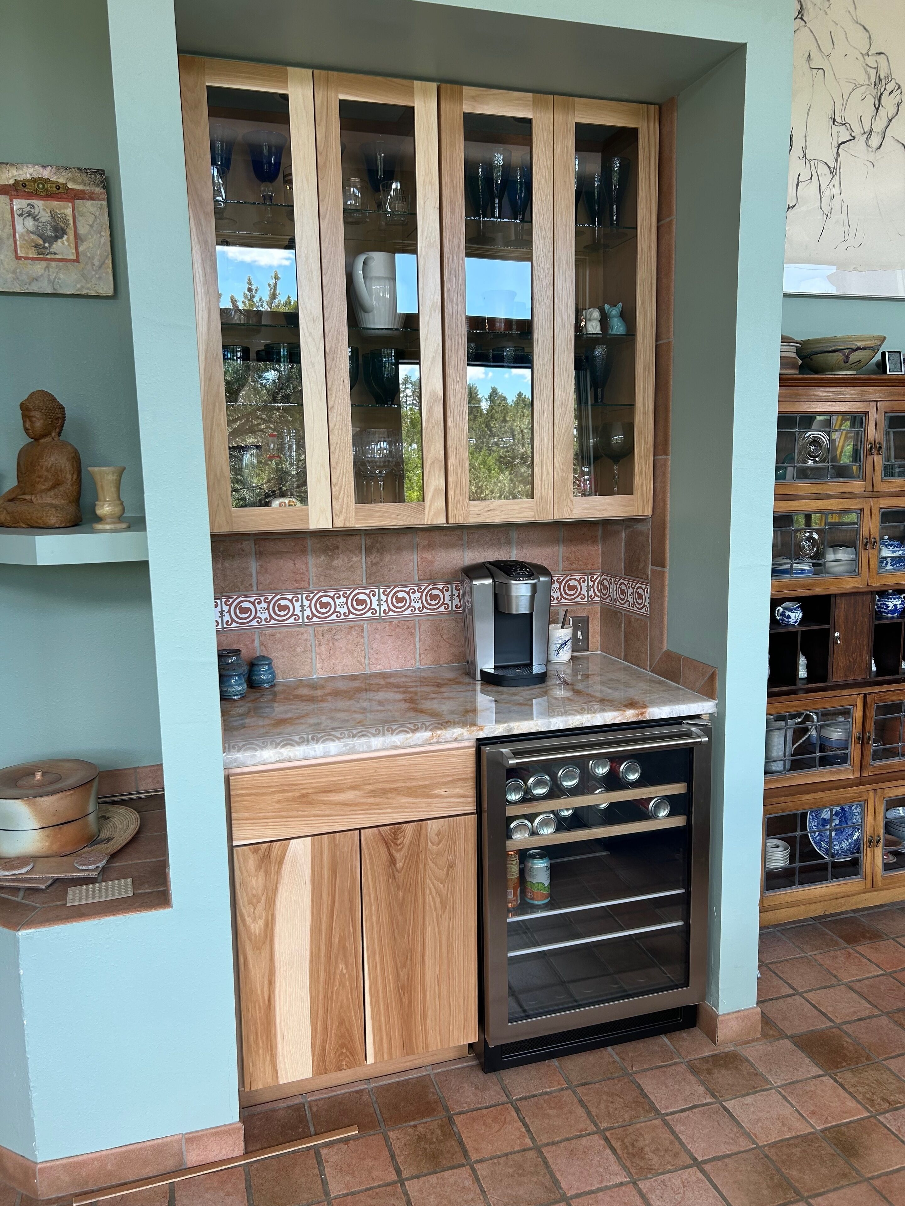 Uma cozinha compacta com armários de madeira, forno embutido e cafeteira.