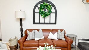 A brown leather sofa with white and gray pillows, a woven basket, a floor lamp, and a small round table. - 🐄The Farm House 🐄 POOL IS OPEN!!! (Washington)