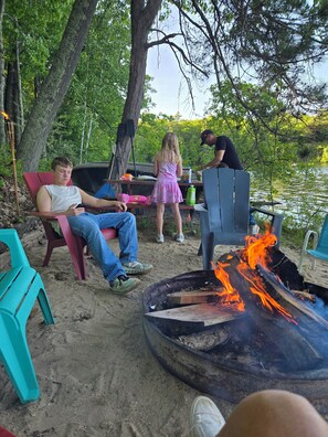 Un terrain de camping équipé d’un foyer, de sièges et offrant une vue sur un lac.