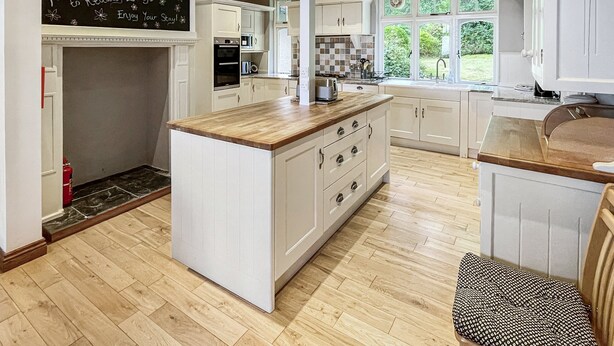 A modern kitchen with white cabinetry, a wooden island, and a chalkboard sign. - Redway Lodge, Porlock (Porlock)