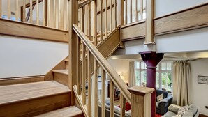 A wooden staircase leading to a living area with a sofa and a window. - Redway Lodge, Porlock (Porlock)