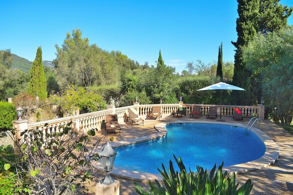 A swimming pool surrounded by a stone deck, with a railing and lounge chairs. - Rural and friendly, Casa de Mercedes Pollensa 057 (Pollensa)