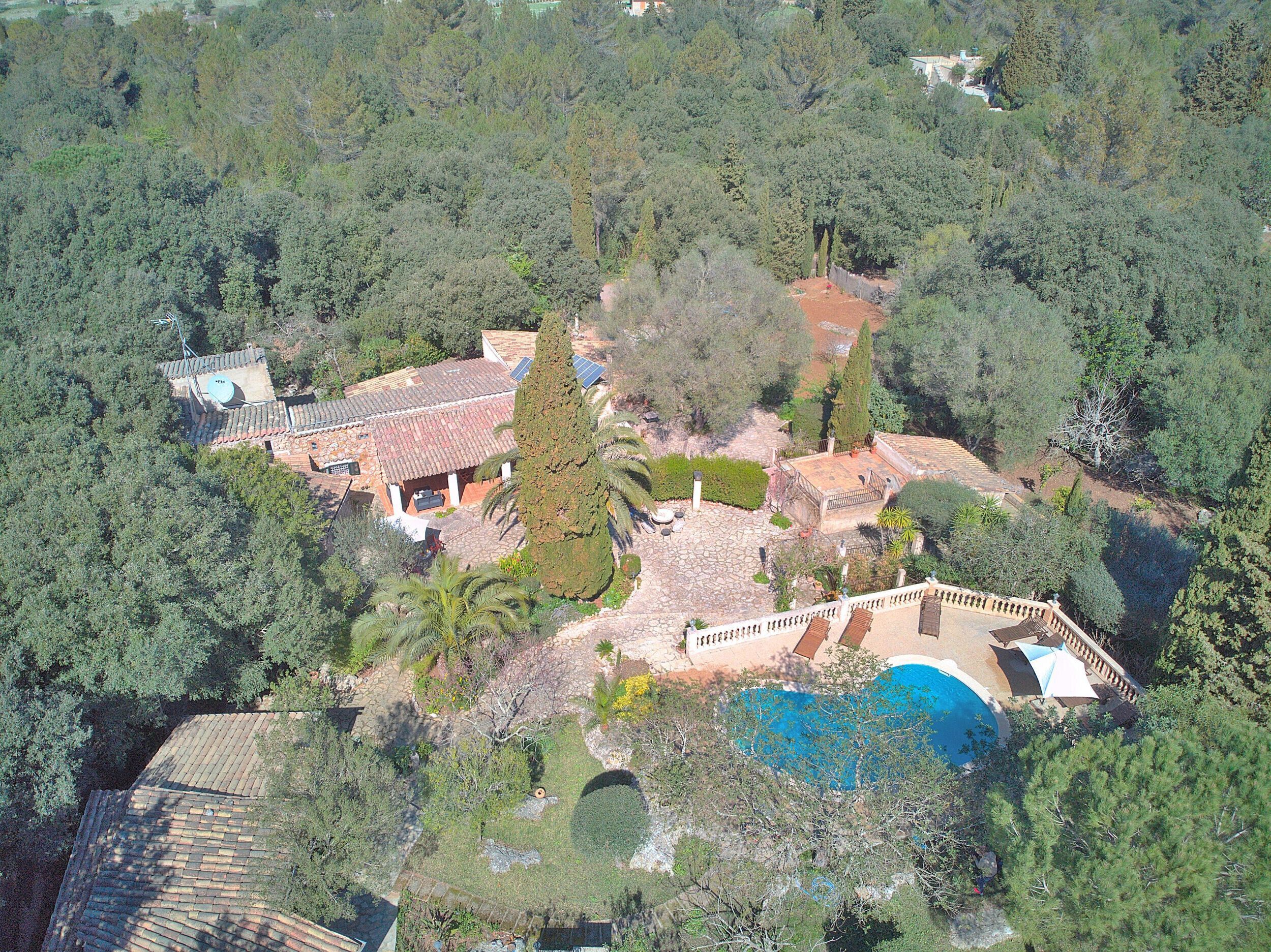 An aerial view of a property with a swimming pool, a covered patio, and a garden.