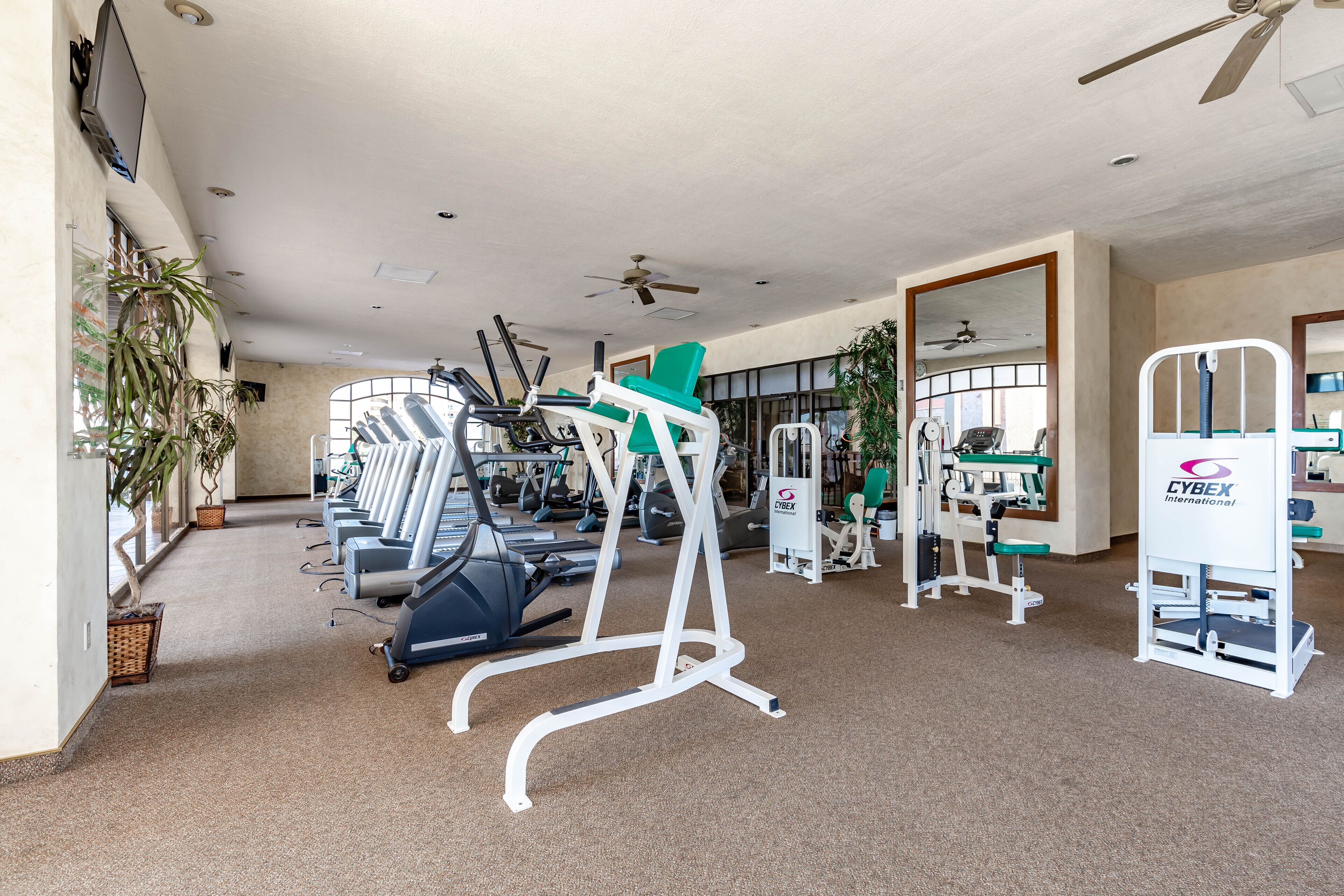 Une salle de sport équipée de tapis de course, de vélos d’appartement et d’appareils de musculation.