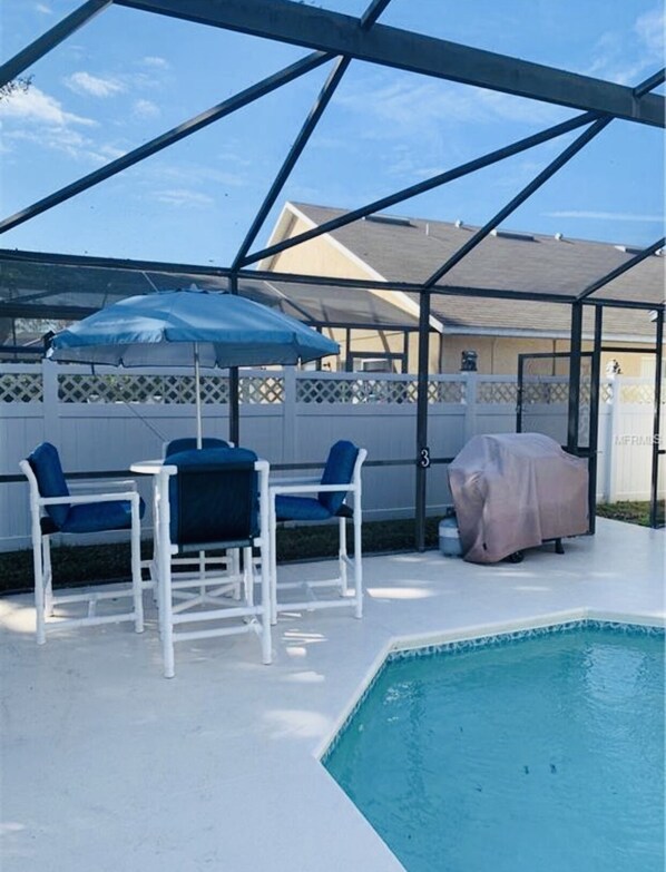 Relax by the pool with a meal prepared on the grill, surrounded by an outdoor space with a table and chairs.