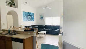 A modern living room with a black leather sofa, a dining area with a kitchen island, and a ceiling fan. - PROMO 10% WEEKLY/15% MONTHLY DISCOUNT
Your Magical Oasis Awaits, Disney Is near. (Kissimmee)