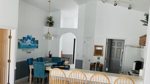 A modern kitchen with a central island, bar stools, and a dining area with blue chairs. - PROMO 10% WEEKLY/15% MONTHLY DISCOUNT
Your Magical Oasis Awaits, Disney Is near. (Kissimmee)