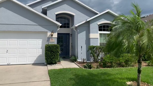 A two-story house with a garage, a front door, and a small front yard with a palm tree. - PROMO 10% WEEKLY/15% MONTHLY DISCOUNT
Your Magical Oasis Awaits, Disney Is near. (Kissimmee)