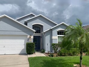 Stylish home with a garage and lawn, featuring a palm tree.