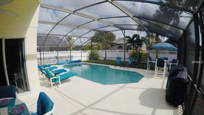 A covered outdoor swimming pool with lounge chairs and a table. - PROMO 10% WEEKLY/15% MONTHLY DISCOUNT
Your Magical Oasis Awaits, Disney Is near. (Kissimmee)