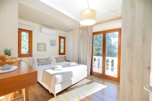 A bedroom with a bed, a wooden desk, a window, and a balcony.