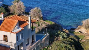 A coastal building with a tiled roof, a balcony, and a view of the sea.