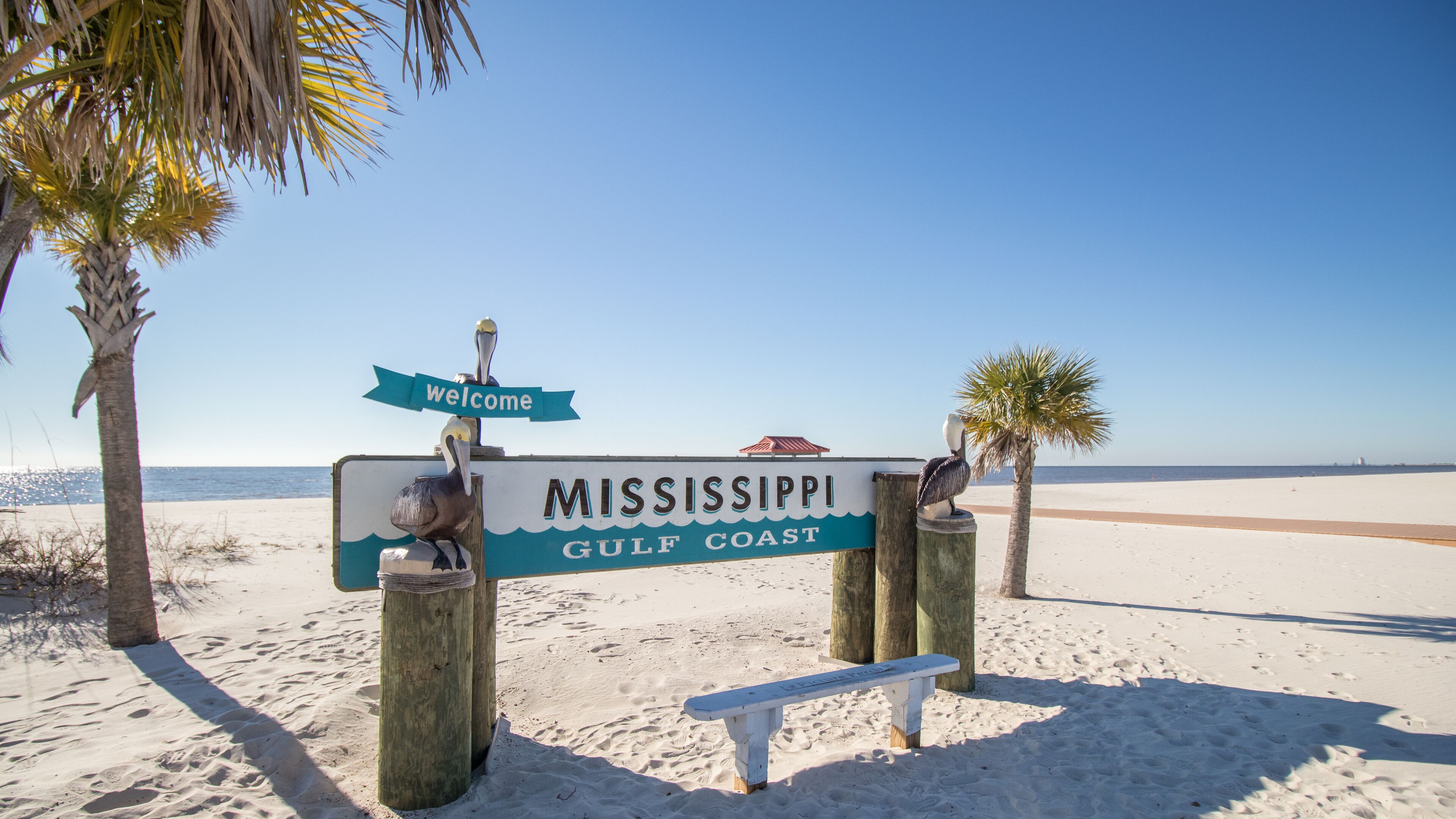 Un cartel de playa con la frase 'Mississippi Gulf Coast' y un letrero de 'Bienvenido'.