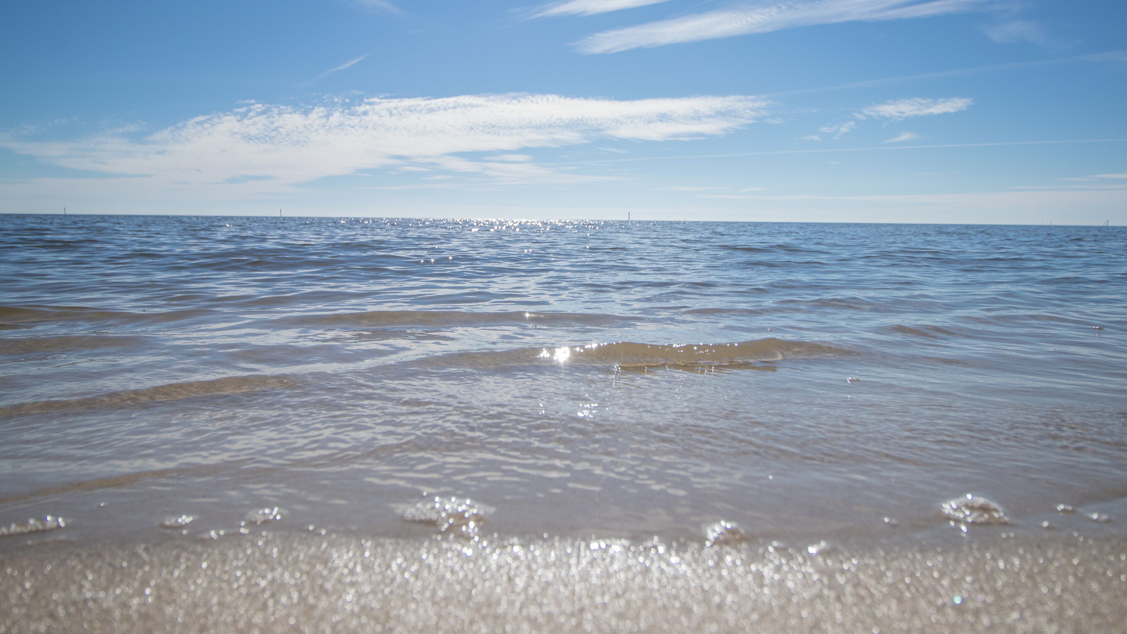 Ein Strand mit klarem Wasser und einer entfernten Skyline einer Stadt.