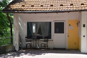 Ein kleines Gebäude mit Ziegeldach, einem Fenster mit Vorhang und einer Tür mit Hausnummer.