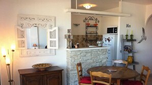 A cozy kitchen with a stone island, wooden cabinets, and a dining table with chairs. - Le Marina (L'île-Rousse)