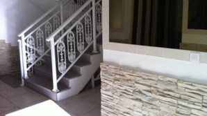 A staircase with ornate metal railings, a stone wall, and a large window. - Le Marina (L'île-Rousse)