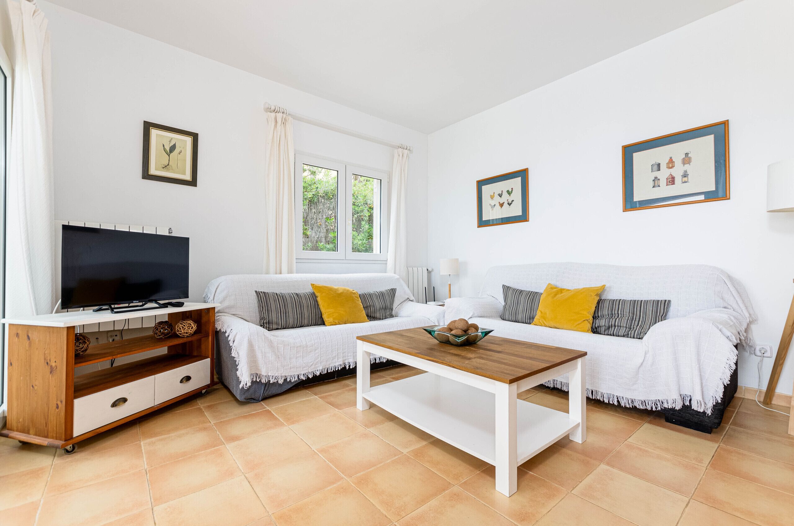 A living room with a TV, two sofas, a coffee table, and a wooden cabinet.